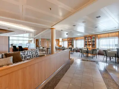 Blick in die helle und modern eingerichtete Bibliothek mit Sitzbereichen an Bord der Seabourn Quest.