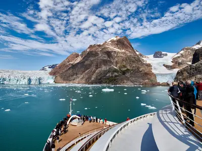 Passagiere an Bord der Seabourn Quest blicken vom Außendeck auf gigantische Gletscher und Eisberge in Grönland.