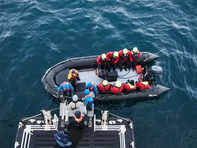 Ein schwarzes Zodiac-Schlauchboot mit Passagieren an Bord der Seabourn Quest auf dem tiefblauen Meer.