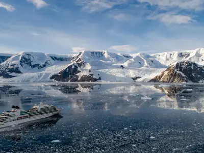 Das luxuriöse Kreuzfahrtschiff Seabourn Quest fährt durch das von Eisschollen bedeckte Wasser der Antarktis vor gewaltigen Gletschern.