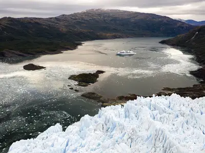 Luftaufnahme der Seabourn Quest in einer chilenischen Bucht mit schmelzendem Gletschereis und Bergen im Hintergrund.