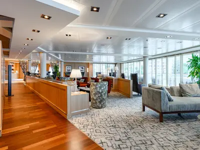 Die gemütliche und stilvoll eingerichtete Lounge an Bord der Seabourn Quest bietet komfortable Sessel, warme Holzelemente und viel Tageslicht.