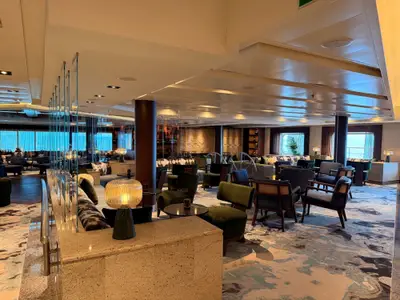Blick in die stilvoll eingerichtete Lounge an Bord der Seabourn Quest mit bequemen Sesseln, warmen Lampen und Ausblick auf das Meer.