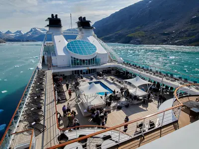 Das Pooldeck der Seabourn Quest mit Passagieren, Liegestühlen und einem Pool inmitten einer arktischen Fjordlandschaft mit Eisbergen.