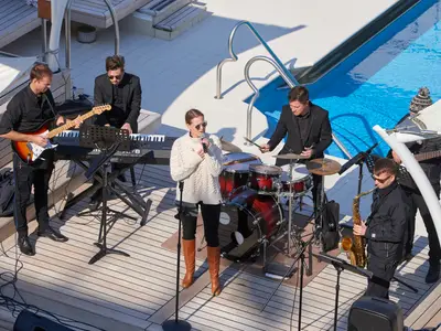 Eine Live-Band mit Sängerin und Musikern tritt auf dem sonnigen Pooldeck an Bord der Seabourn Quest auf.