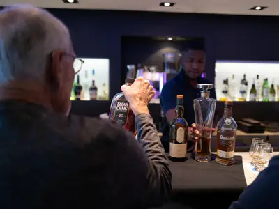 Ein Gast begutachtet an Bord der Seabourn Sojourn eine edle Flasche Bourbon an der Bar im Beisein des Barkeepers.