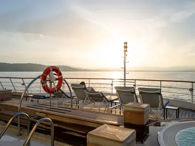 Sonnendeck der Seabourn Sojourn mit Liegestühlen und einem Rettungsring vor dem glitzernden Meer bei Sonnenuntergang.