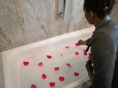 Ein Crew-Mitglied an Bord der Seabourn Sojourn dekoriert ein schäumendes Bad in einer Suite mit roten Rosenblättern.