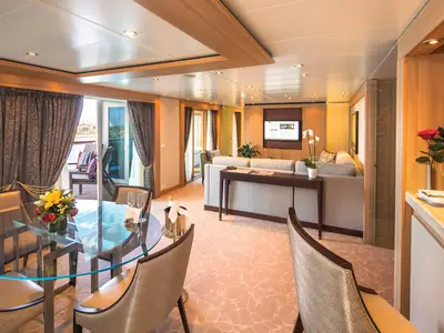 Einblick in die elegante und geräumige Wintergarden Suite an Bord der Seabourn Sojourn mit Esstisch, Sofa und Balkon.