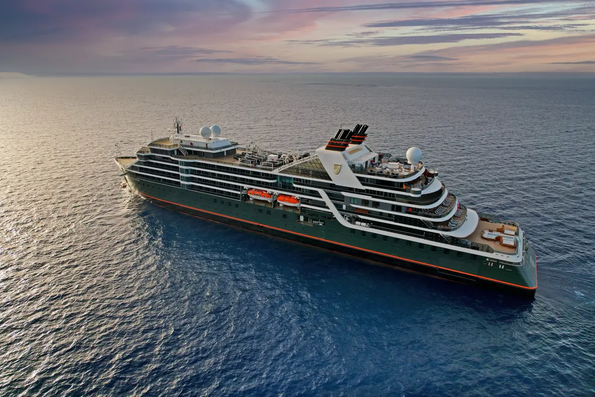 Luftaufnahme der Seabourn Venture, ein luxuriöses, dunkelgrünes Expeditionsschiff auf dem Meer während des Sonnenuntergangs.