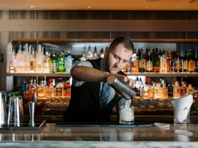 Ein Barkeeper an der edel ausgestatteten Bar an Bord der Seabourn Venture bereitet sorgfältig einen Cocktail zu.