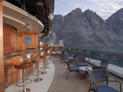 Die gemütliche Sky Bar an Bord der Seabourn Venture lädt zum Verweilen vor einer Kulisse aus steilen, dunklen Bergen ein.