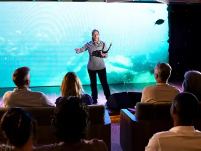 Eine Crew-Mitarbeiterin präsentiert Schnorchelausrüstung vor Passagieren an Bord der Seabourn Venture.