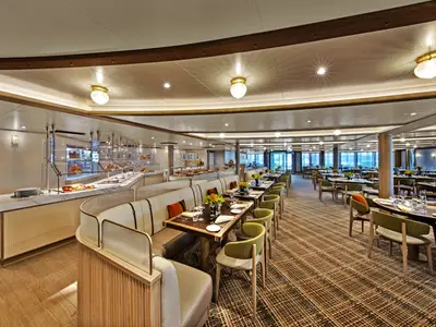 Das elegant gestaltete Buffet-Restaurant an Bord der Seabourn Venture mit gedeckten Tischen, Sitzbänken und Buffet-Stationen.