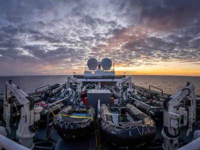 Blick auf das Außendeck der Seabourn Venture mit aufgereihten Zodiac-Schlauchbooten unter einem wolkenverhangenen Abendhimmel auf dem Meer.