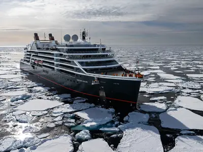 Luftaufnahme der Seabourn Venture inmitten von treibenden Eisschollen auf dem tiefblauen Polarmeer unter leicht bewölktem Himmel.