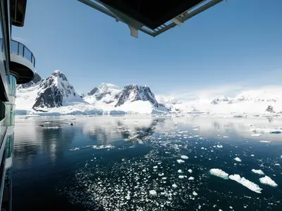 Blick von einem Deck der Seabourn Venture auf schneebedeckte Berge, Treibeis und Schlauchboote in der Antarktis.