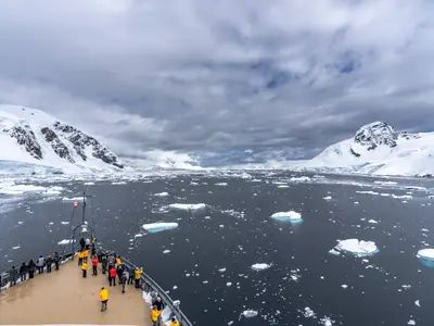 Gäste auf dem Außendeck der Seabourn Venture blicken auf eine weite polare Landschaft mit Eisbergen und Gletschern in der Antarktis.