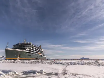 Das Expeditionsschiff Seabourn Venture im dicken Packeis der Antarktis mit Passagieren auf der Eisfläche.