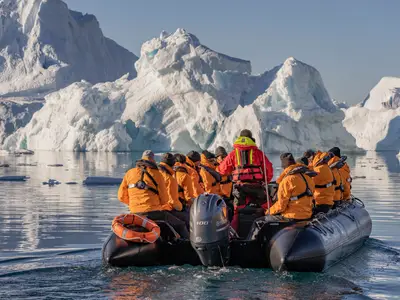 Passagiere an Bord der Seabourn Venture fahren in einem Zodiac-Schlauchboot nahe an riesigen Eisbergen vorbei.
