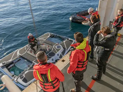 Passagiere und Crew an Bord der Seabourn Venture beobachten das Herablassen eines U-Boots ins Meer.
