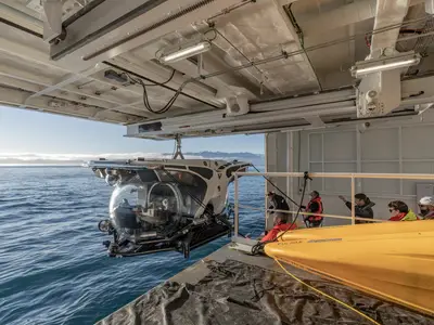 Ein gelb-weißes U-Boot wird an Bord der Seabourn Venture ins Wasser gelassen, während Passagiere zuschauen.