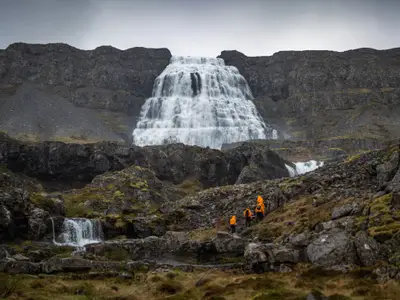 Wandergruppe an Bord der Seabourn Venture nähert sich einem riesigen, kaskadenartigen Wasserfall in einer felsigen Landschaft.