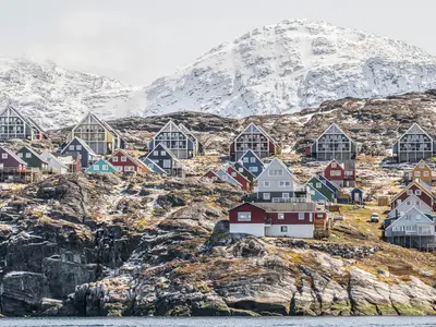 Bunte Holzhäuser an einem Berghang in Grönland während eines Landausflugs der Seabourn Venture.