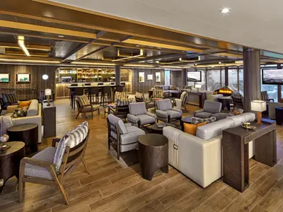 Eine gemütlich eingerichtete Lounge an Bord der Seabourn Venture mit stilvollen Sesseln, Holzdekor und einem warmen Kamin im Hintergrund.