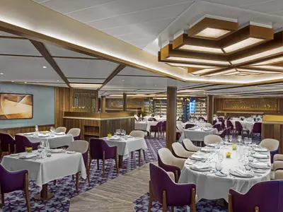 Elegantes Restaurant an Bord der Seabourn Venture mit stilvoll gedeckten runden und eckigen Tischen, lila Stühlen und warmer Deckenbeleuchtung.