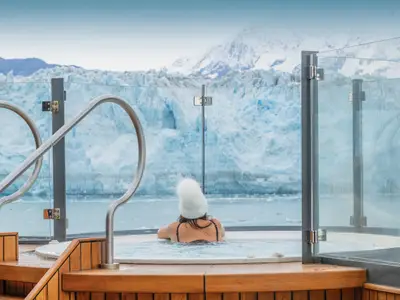 Eine Frau entspannt im Whirlpool an Bord der Seabourn Venture und blickt auf einen riesigen arktischen Gletscher.