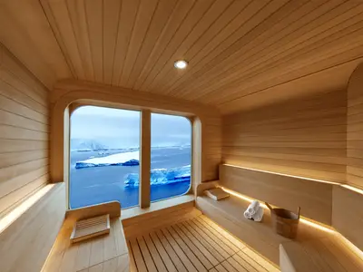 Blick aus der Holzsauna an Bord der Seabourn Venture auf vorbeigleitende Eisberge in einer polaren Landschaft.