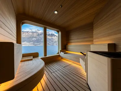 Blick aus der gemütlichen Holzsauna an Bord der Seabourn Venture durch das große Panoramafenster auf eisige Berge und blaues Wasser.