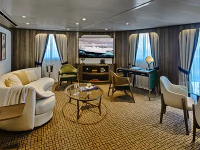 Blick in den großzügigen Wohnbereich einer eleganten Suite an Bord der Seabourn Venture mit Sofaecke und Schreibtisch.
