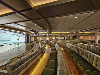 Der Vortragssaal Discovery Center an Bord der Seabourn Venture mit geschwungenen grünen Sitzbänken und einer großen Leinwand mit Eisbären-Motiv.