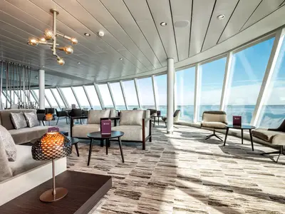 Die helle und moderne X-Lounge an Bord der Mein Schiff 1 bietet durch bodentiefe Fenster einen weiten Blick auf das offene Meer. Bequeme Sessel und Sofas laden zum Verweilen ein.