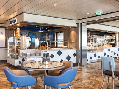 Innenansicht der modernen Backstube an Bord der Mein Schiff 1 mit gefuellten Auslagen, Buffet-Theke und einladenden Sitzbereichen.
