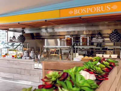 Die Bosporus Snackbar an Bord der Mein Schiff 1. Zu sehen sind Döner-Spieße (Kalb und Hähnchen), eine Auswahl an frischen Salaten, Saucen und Brot in einer modernen, hellen Umgebung.
