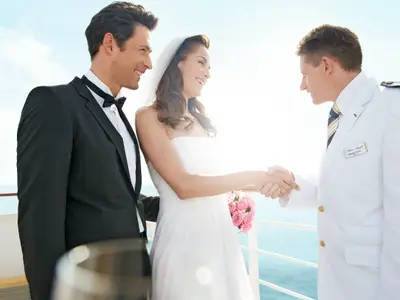 Ein Brautpaar schüttelt Kapitän Michael Block die Hand auf dem Außendeck der Mein Schiff 1. Sie heiraten bei strahlendem Sonnenschein mit Meerblick.