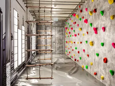Kletterbereich im Kinderclub der Mein Schiff 1 mit Seilleiter, bunter Kletterwand und Schwarz-Weiss-Gebäudemalerei.