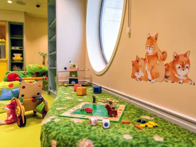 Ein liebevoll eingerichteter Baby- und Kleinkindbereich mit bunten Spielsachen, weichen Sitzsäcken und Tiermalereien an Bord der Mein Schiff 1.