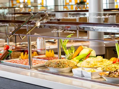 Ein reichhaltiges Salat- und Wurstbuffet mit verschiedenen Gerichten und Zutaten, darunter Kartoffelsalat, Bohnensalat und Wurstspezialitäten, an Bord der Mein Schiff 2.