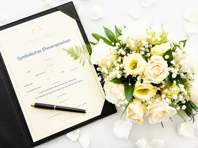Dokument für Eheversprechen von Mein Schiff. Brautstrauß mit weißen und gelben Blumen, Stift und Blütenblätter. Romantische Trauung an Bord.