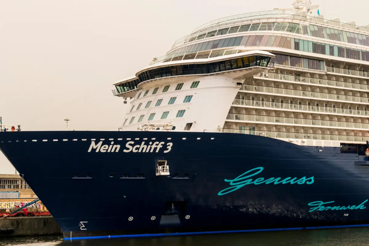 Aussenansicht des Kreuzfahrtschiffs Mein Schiff 3 im Hafen, mit den Schriftzügen Genuss und Fernweh.