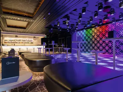 AbtanzBar an Bord der Mein Schiff 5. Moderne Club-Lounge mit Bar, Sofas, Stehtischen. Tanzfläche mit Regenbogen-Wand und Bodenspots. Ohne Personen.
