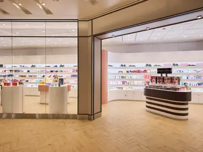 Ein gut beleuchteter Sephora-Shop an Bord der Mein Schiff 7, mit Regalen voller Kosmetikprodukte, Parfüms und Make-up-Displays. Der Shop hat einen modernen, hellen und offenen Look mit Holzfußboden und weißen Wänden.