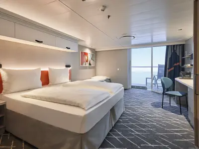 Innenansicht einer hellen und modernen Kabine auf der Mein Schiff Flow mit zwei Einzelbetten, einem Beistellbett, einem Schreibtisch mit Stuhl und einem Balkon mit Meerblick. Die Kabine ist in Grau-, Weiß- und Orangetönen gehalten und verfügt über Stauraum über den Betten.