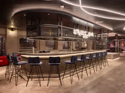 Die Street Art Bar an Bord der Mein Schiff Relax zeigt einen langen Tresen mit vielen blauen Barhockern und einer auffälligen Neon-Schrift, die 'STREET ART BAR' leuchtet. Hinter der Bar befinden sich Flaschen und dekorative Gitterstrukturen. Eine beeindruckende Lichtinstallation an der Decke zieht sich durch den Raum.