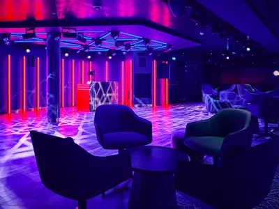 Der D4 Club & Lounge auf der Mein Schiff Relax ist in lebhaftes Lila und Rot getaucht, mit futuristischen Neonlichtern, einer DJ-Kabine und gemütlichen Sitzgelegenheiten.