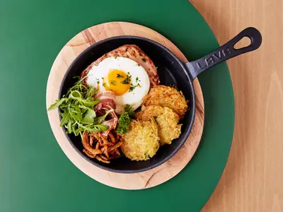 Ein herzhaftes Gericht mit Spiegelei, knusprigem Rösti, Bacon, Wurst und frischem Rucola, serviert in einer gusseisernen Pfanne an Bord der Mein Schiff Relax.